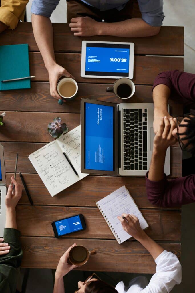 Overhead view of a creative team working on laptops and tablets during a strategy session.